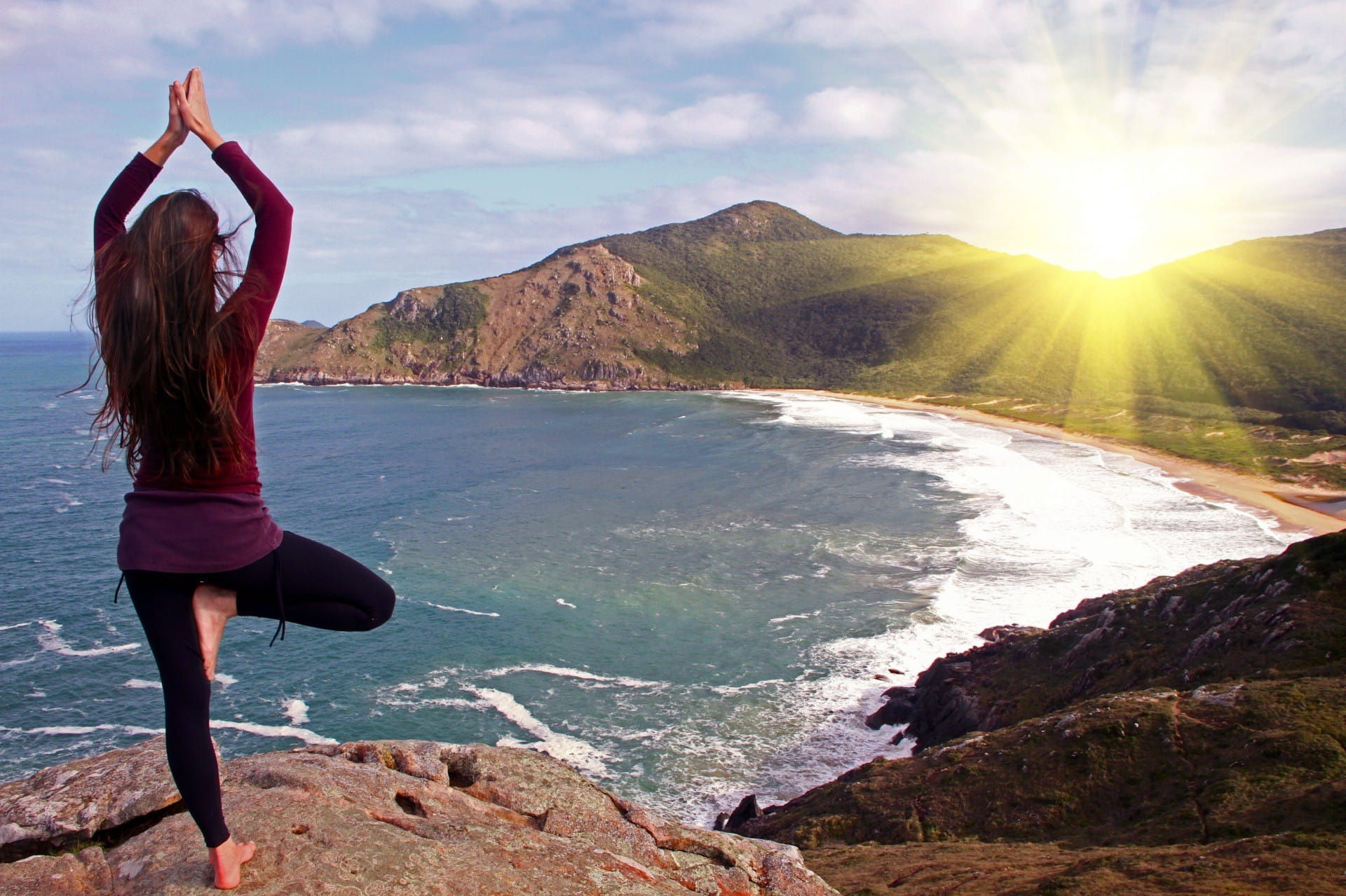 Une femme faisant de l'exercice de yoga en regardant le soleil.