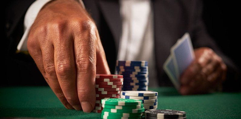 Une main empilant des jetons de casino sur une table.
