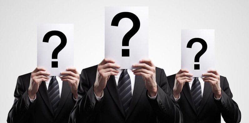 Tres personas tienen en sus manos hojas con signos de interrogación