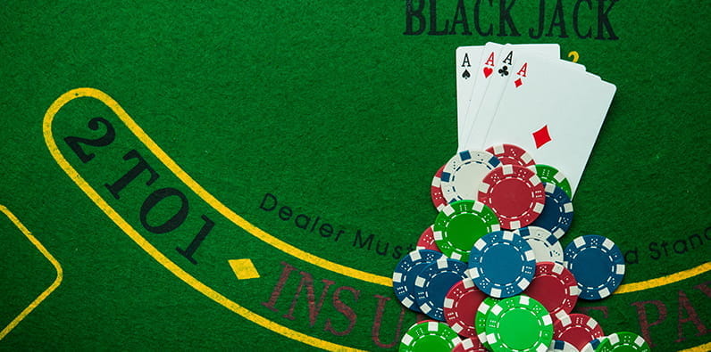 Une table de blackjack avec des jetons de casino et quatre cartes d'as.