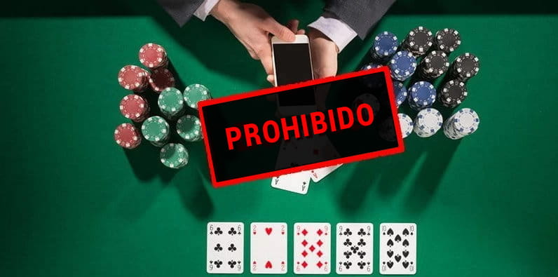 Une table de casino avec des jetons, des cartes de poker et quelques mains ayant un mobile.
